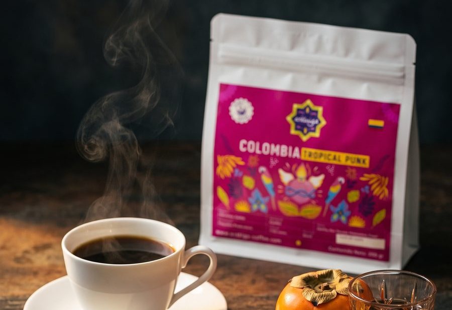 Bolsa de Colombia Tropical Punk de Arábiga junto a una taza de café humeante