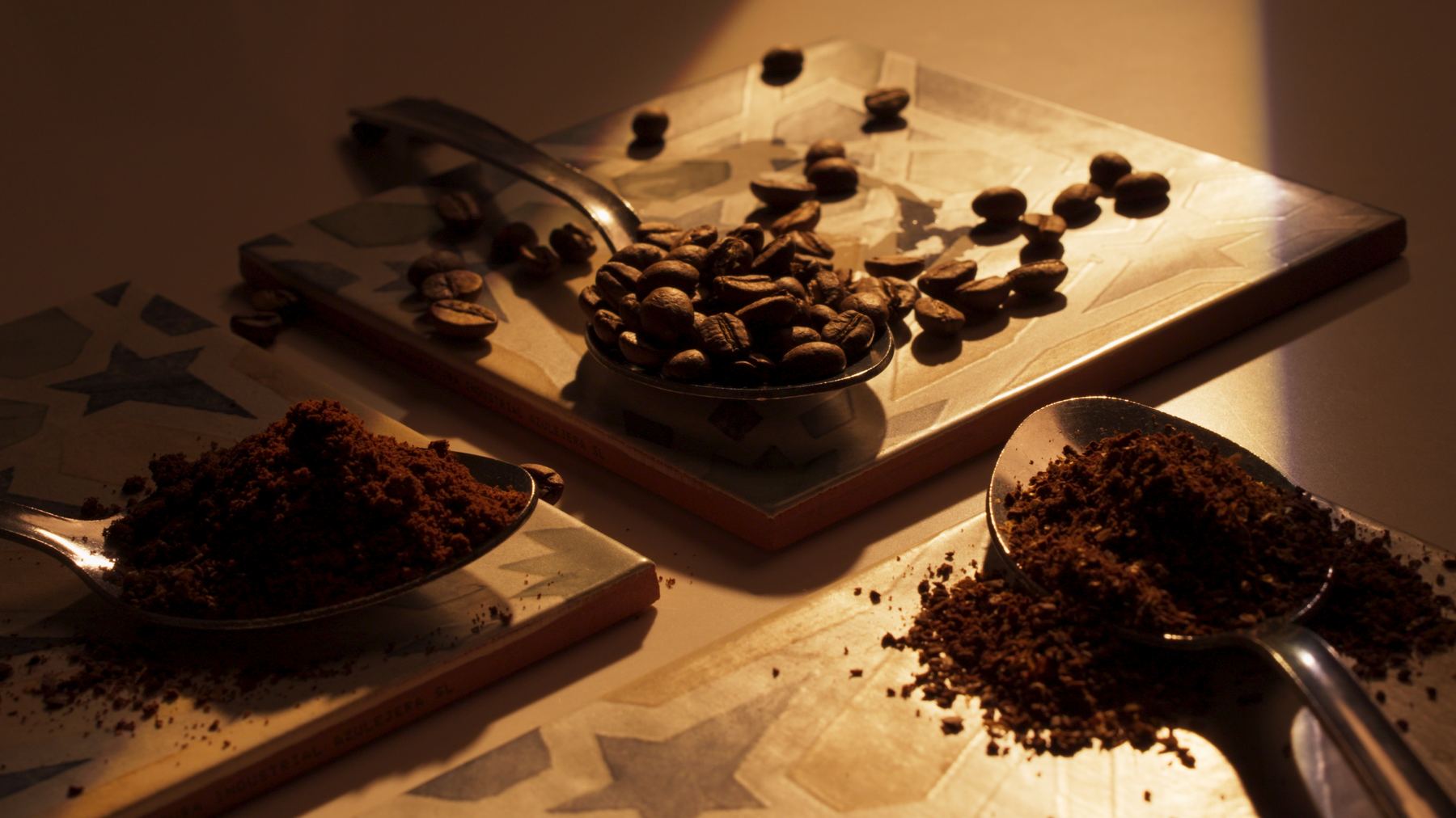 Cucharas con granos de café tostados y café molido sobre una tabla